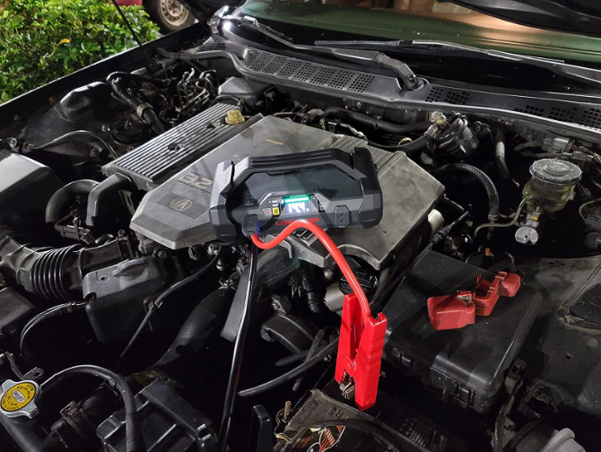 Jump starter connected to car battery under hood.