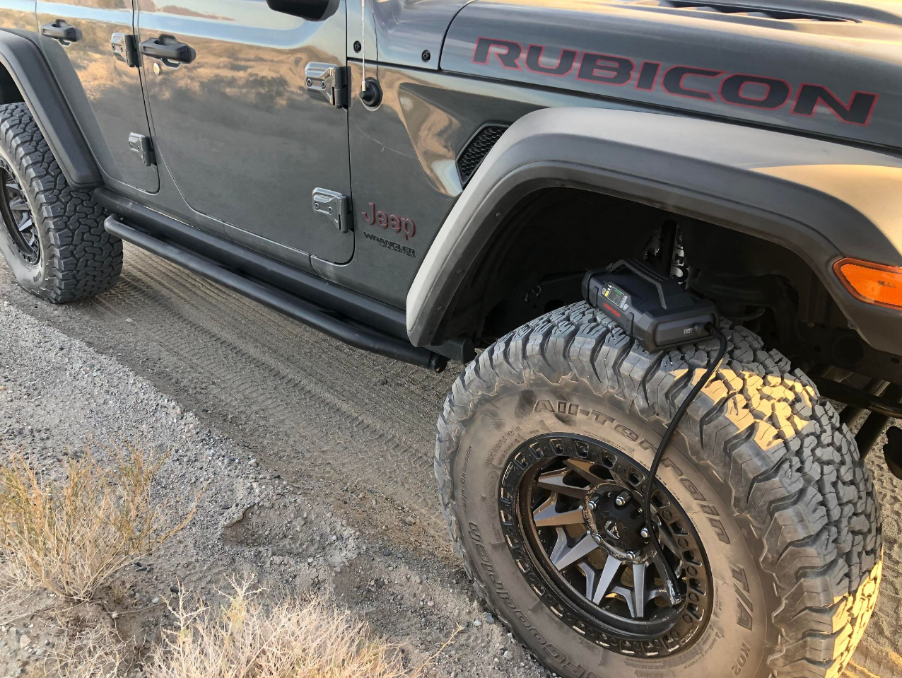 Off-road vehicle with a tire inflator in use on rugged terrain.