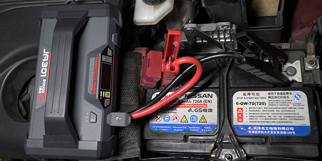 Emergency jump starter connected to car battery.